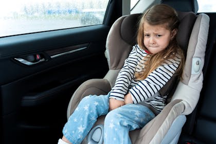little girl in car seat needing a wee