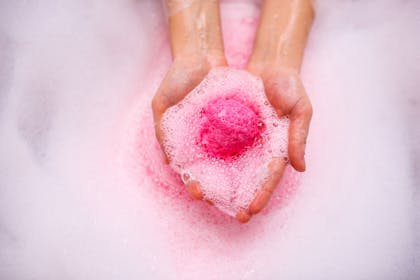 A person holding a pink bath bomb