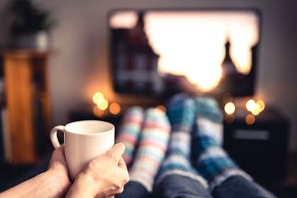 Two people watching a film with a hot drink and wearing cosy socks
