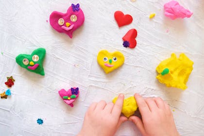 Child making heart faces with play dough
