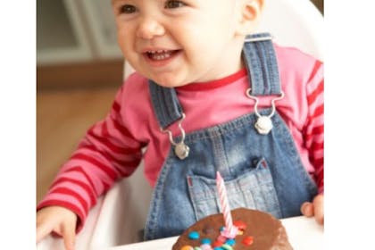 baby sitting in highchair with birthday cake