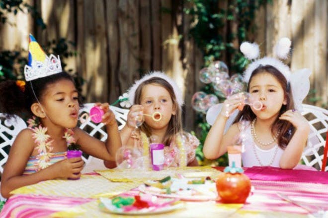 Girls blowing bubbles at a party table