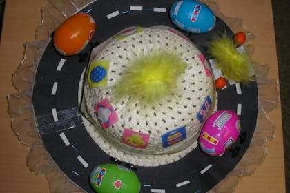 Easter hat decorated to look like a road with egg cars