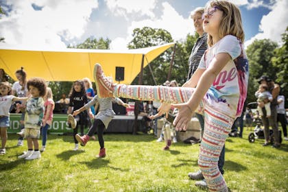 Kids dancing at music festival party next to small yellow stage