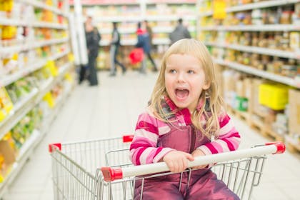 Happy child sitting in a supermarket trolley