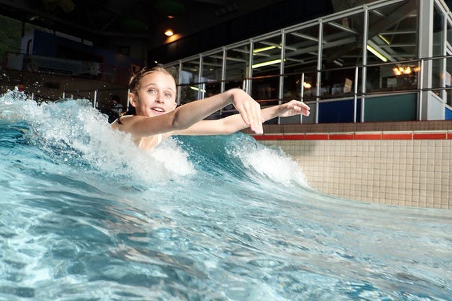 little girl swimming in a wave machine at a swimming pool
