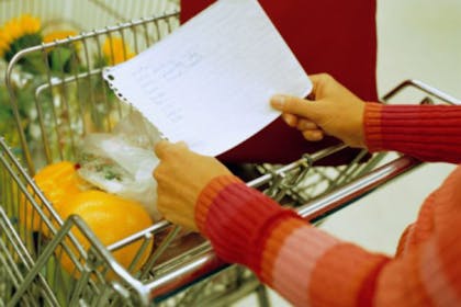 woman holding paper and pushing trolley with food in it