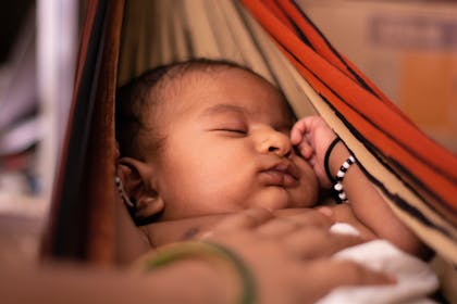 Baby girl asleep in red hammock 