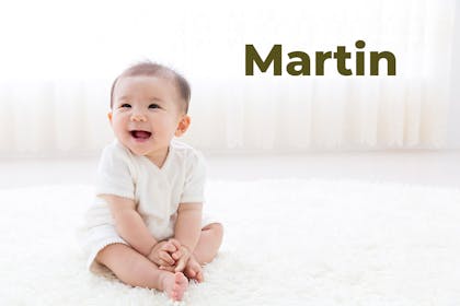 Baby sitting up and laughing. Name Martin written in text
