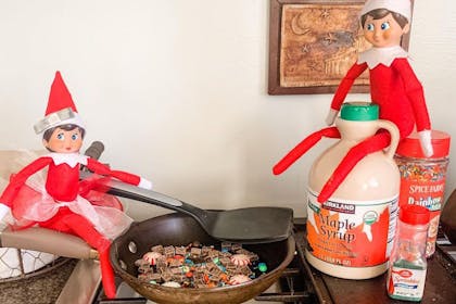 Christmas Elf on the Shelf frying sweetie breakfast made from chocolate, maple syrup and cake sprinkles