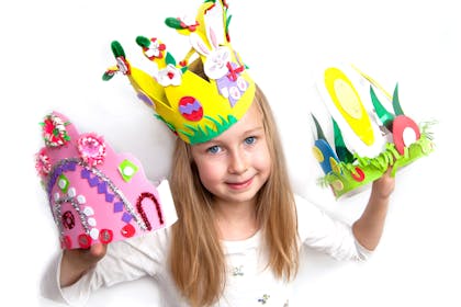 Girl wearing an Easter crown and holding more Easter bonnets/hats
