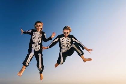 Two kids dressed as skeletons bouncing on trampoline