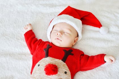 Sleeping baby wearing Santa hat and red Rudolf jumper