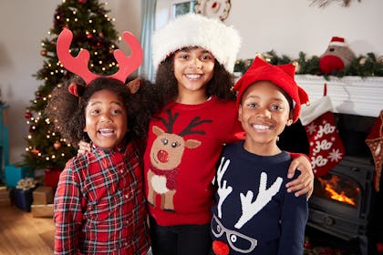 Three kids wearing Christmas jumpers