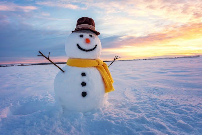 Snowman with scarf and hat on orange sunset background 