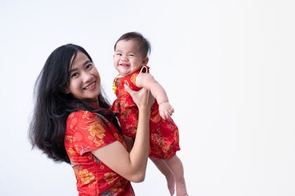 Mum holding baby wearing new red clothing for Chinese New Year