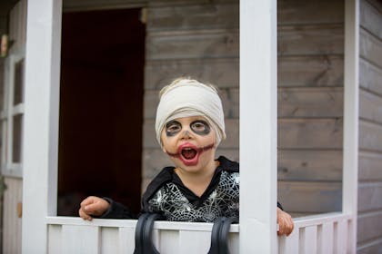 Toddler dressed in zombie costume with bandages wrapped round head and face paint on for Halloween party