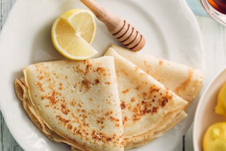 Crêpes on a plate with lemon slices and honey