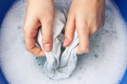 close up of woman's hands washing clothes in soapy water