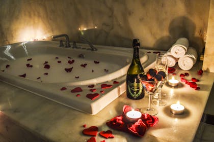 Romantic bath with rose petals, candles and wine