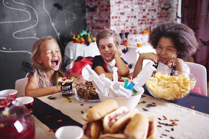 Kids dressed in Halloween costumes laughing at the table