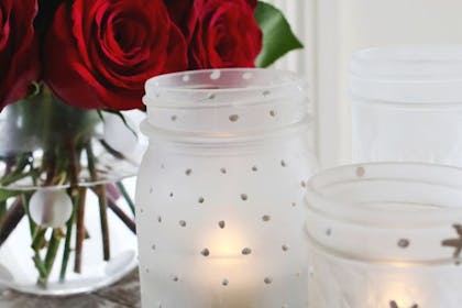 Mason jars decorated with frosting spray as candle holders