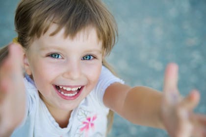 girl smiling with arms up