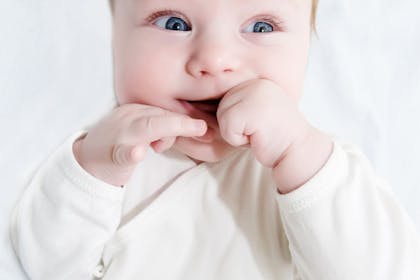 Happy baby chewing on fingers