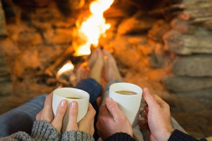 Hands holding hot drinks in front of fire