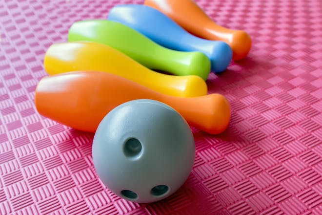 Grey bowling ball and multicoloured plastic skittles for party game