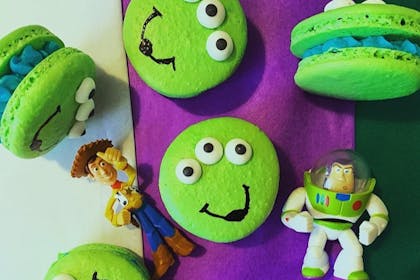 Macarons baked to look like Toy Story aliens next to model Woody and Buzz Lightyear