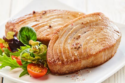 Two tuna steaks on a plate with salad