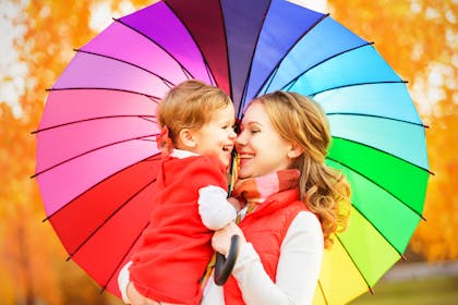 Mum and daughter under a rainbow umbrella