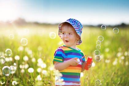 Baby excited by bubbles in a field