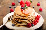 Stack of American pancakes with berries and syrup