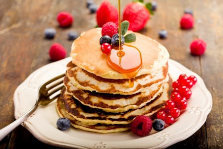 Stack of American pancakes with berries and syrup