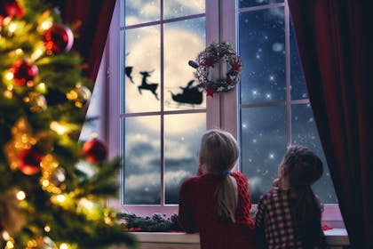Children watching Santa's sleigh in the sky outside window