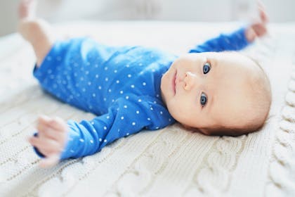 eight week old baby lying down in blue and white spotty babygro