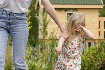 Mum pulling child away from playground