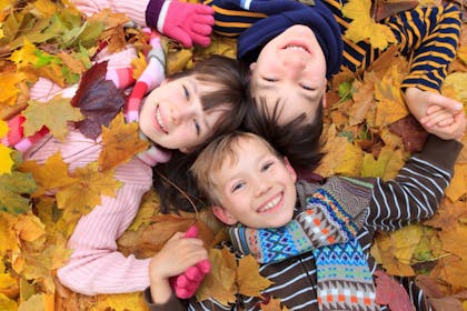 children laying in autumn leaves