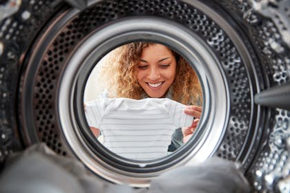 woman looking at clean laundry from washing machine
