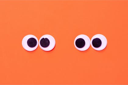 Craft googly eyes against bright orange background 