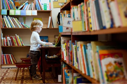 A toddler chooses a picture book off the shelf in a library