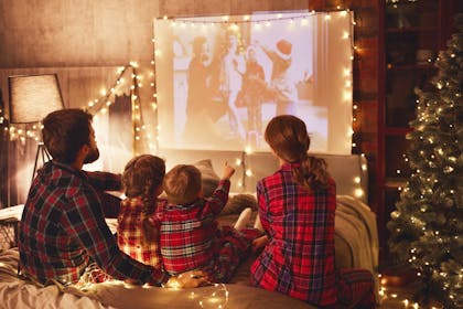 Family in matching festive pyjamas watching Christmas TV 