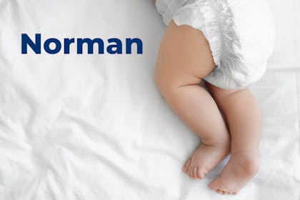 Baby's legs on bed in nappy. Name Norman written in text
