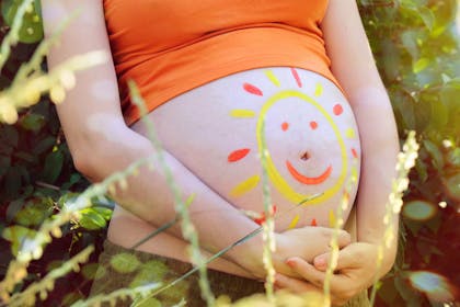 Pregnant woman with sunshine on her bump for hot weather survival tips