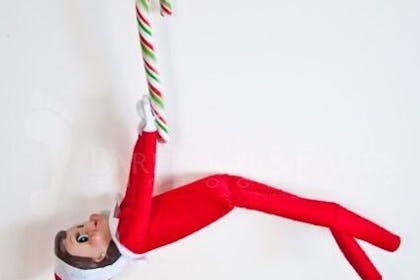 Elf on the Shelf holding onto candy cane sweets 
