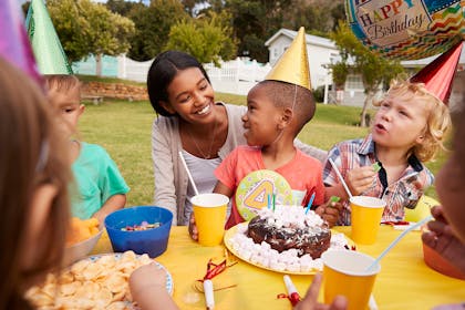 Four year old's birthday party with children sitting round party table and cake