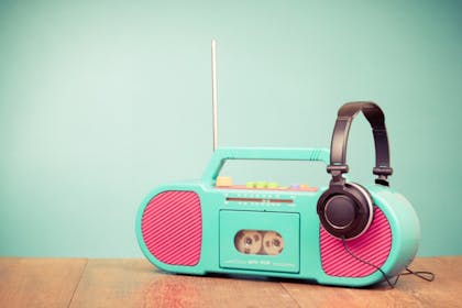 pink and blue tape player with headphones on wooden table with blue background