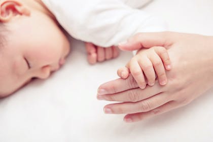 Baby sleeping holding hands with parent